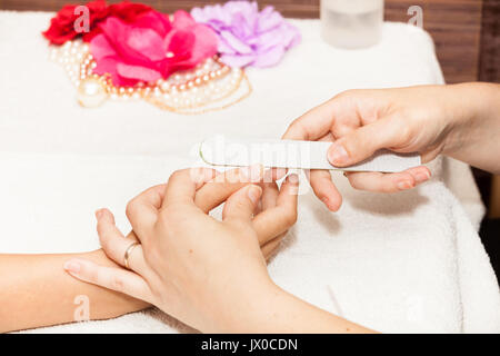 L'esthéticienne polish les ongles de la cliente avant de mettre du vernis à ongles Banque D'Images