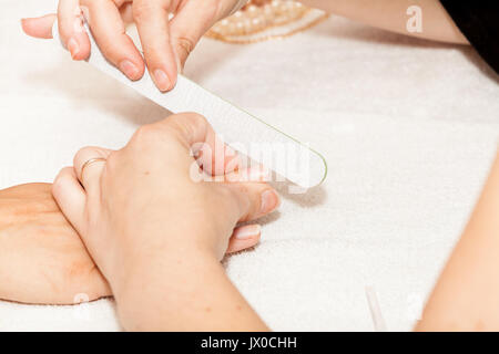 L'esthéticienne polish les ongles de la cliente avant de mettre du vernis à ongles Banque D'Images