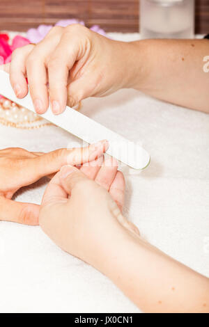 L'esthéticienne polish les ongles de la cliente avant de mettre du vernis à ongles Banque D'Images