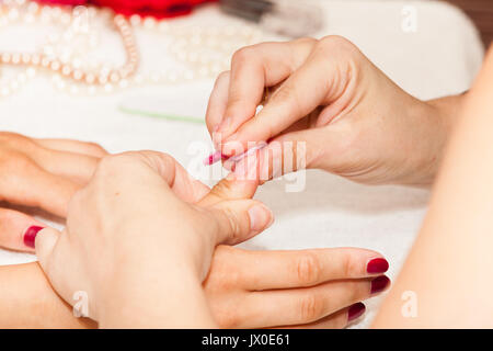 L'esthéticienne élimine l'ancien vernis à ongle avec un coton et de suppression Banque D'Images