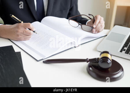 Avocat part écrit le document en cour (la justice, le droit) avec son bloc. Banque D'Images