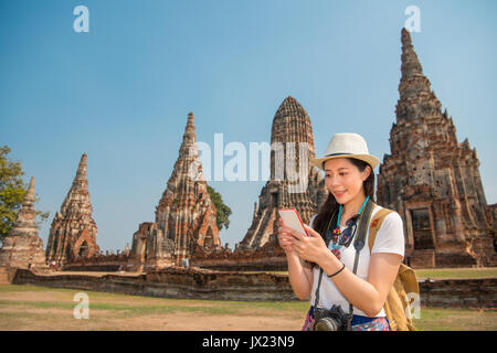Asian woman using smartphone à la recherche carte de Wat Chaiwatthanaram park à Ayutthaya, Thaïlande, l'envoi de messages texte SMS en ligne sur mobile smartphone Banque D'Images