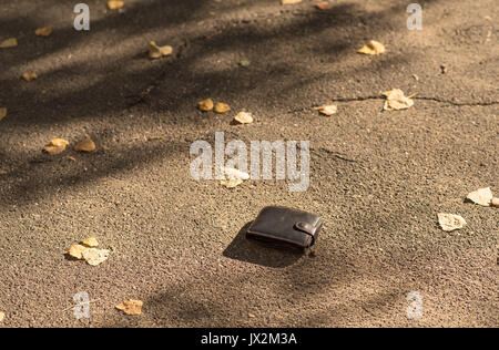 Portefeuille en cuir marron est perdu sur le trottoir Banque D'Images