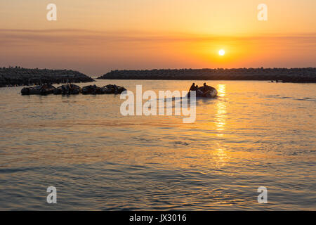 Bateau gonflable zodiac en caoutchouc de quitter un port au lever du soleil dans le Moyen-Orient. Banque D'Images