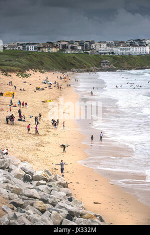 Météo britannique. Les vacanciers s'amuser sur la plage de Fistral malgré les nuages sombres de la cueillette. Banque D'Images