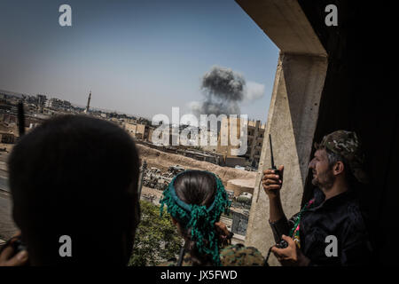 Raqqa, la Syrie. 12Th Aug 2017. Forces Démocratiques syriennes (SDF) soldats regarder par la fenêtre vers un espace d'où la fumée est à la hausse après une attaque aérienne tout en batailles contre l'Etat islamique (est) de la milice de terreur continuent à Raqqa, Syrie, 12 août 2017. (Photo disponible oin 14 août 2017.) Photo : Morukc Umnaber/dpa/Alamy Live News Banque D'Images