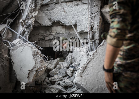 Raqqa, la Syrie. 12Th Aug 2017. Deux soldats armés de la République Les Forces Démocratiques (SDF) d'une recherche dans les débris d'un bâtiment détruit lors de batailles contre l'Etat islamique (est) de la milice de terreur continuent à Raqqa, Syrie, 12 août 2017. (Photo disponible oin 14 août 2017.) Photo : Morukc Umnaber/dpa/Alamy Live News Banque D'Images