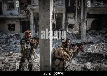 Raqqa, la Syrie. 12Th Aug 2017. Deux soldats armés de la République Les Forces Démocratiques (SDF) debout à côté d'une colonne d'un bâtiment détruit lors de batailles contre l'Etat islamique (est) de la milice de terreur continuent à Raqqa, Syrie, 12 août 2017. (Photo disponible oin 14 août 2017.) Photo : Morukc Umnaber/dpa/Alamy Live News Banque D'Images