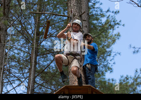 MEZIO, PORTUGAL - 22 juillet 2017 : l'homme aventureux se prépare à une diapositive dans la tyrolienne à travers la forêt. 22 juillet 2017, Mezio, Portugal. Banque D'Images