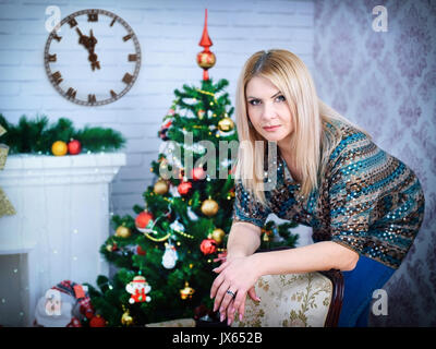 Portrait of smiling young woman showing réveil in front of Christmas Tree Banque D'Images