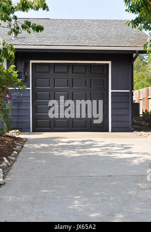 Seul l'extérieur garage voiture avec la porte fermée dans une couleur gris foncé ou gris foncé à l'extrémité d'une allée. Banque D'Images
