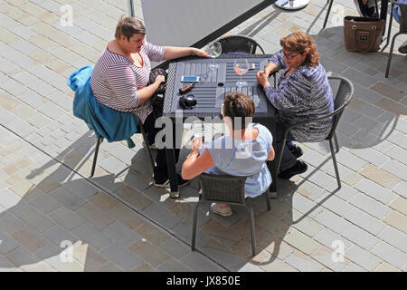 3 mesdames de prendre un cocktail assis au soleil à l'extérieur table bar. Banque D'Images