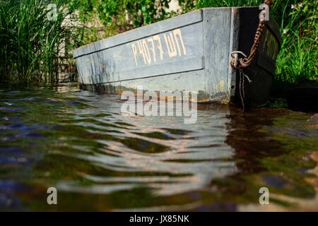 Le bateau de pêcheurs est liée d'une épaisse chaîne sur le rivage d'un lac propre Banque D'Images