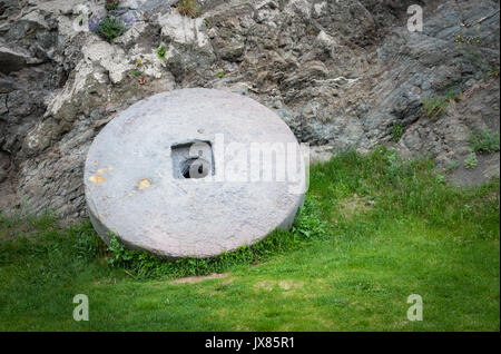 Granit Pierre roue avec jante métal rouillé isolé sur l'herbe verte. Banque D'Images