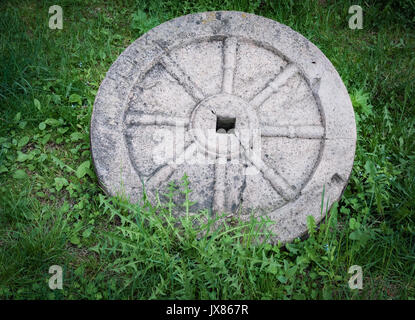 Granit Pierre roue avec jante métal rouillé isolé sur l'herbe verte. Banque D'Images