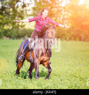 Happy young woman riding cheval au galop au jour d'été ensoleillé. La liberté de l'image concept équestres Banque D'Images