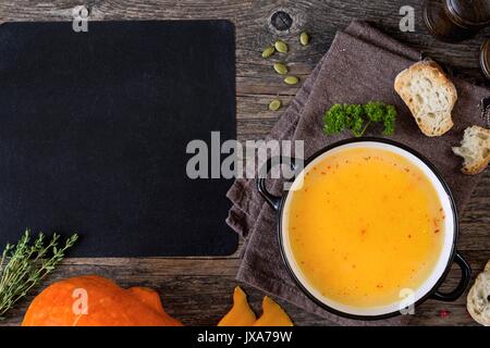 Crème de potiron soupière sur table en bois et tableau noir en blanc pour le texte recette. Vue d'en haut Banque D'Images