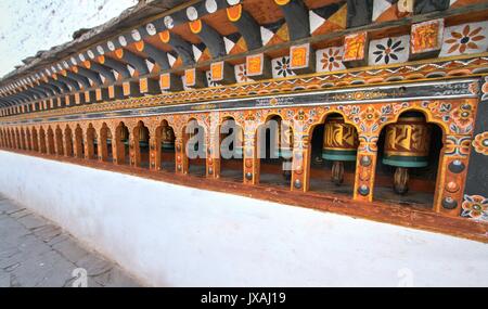 Rangées de roues de prière religieuse colorés à Paro Rinpung Dzong. Monastère bouddhiste et forteresse à Paro, Bhoutan. Banque D'Images