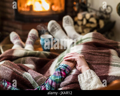 Réchauffement climatique et se reposer près de cheminée. Mère et fille se tenant la main en face du feu. Banque D'Images