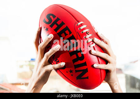 Woman's hands holding Australian rules football ou AFL Banque D'Images