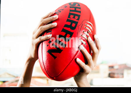 Woman's hands holding Australian rules football ou AFL Banque D'Images