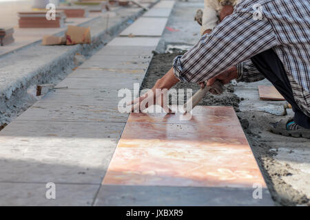 Installe travailleur tuiles sur le plancher. Banque D'Images