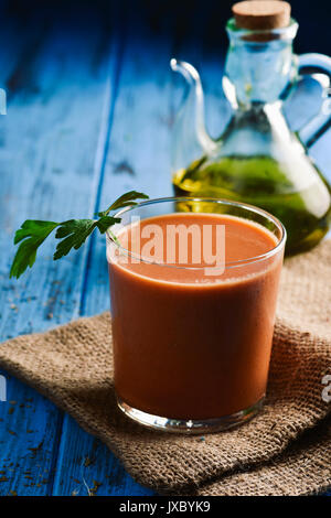 Libre d'un verre rafraîchissant avec le gaspacho, soupe de tomate froide typique espagnol, sur une table rustique en bois bleu, et une burette d'huile d'olive en verre Banque D'Images