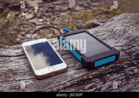 Puissance de charge solaire banque smart phone lying on a log Banque D'Images