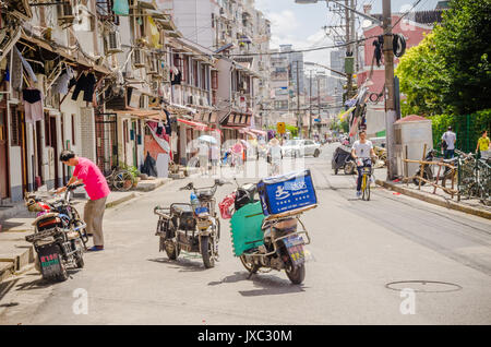 Un couple de scooters électriques sont garées dans le milieu de la route dans un vieux street à Shanghai qui est plein de caractère. Banque D'Images