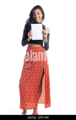 Belle femme est holding a blank billboard. Longueur totale de corps fille brésilienne, pluriethniques, vêtu de noir top et jupe orange. Comité permanent. Banque D'Images