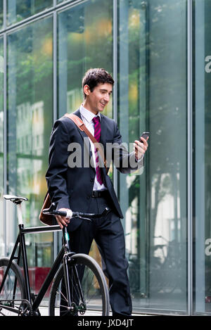 Jeune homme confiant talking on mobile phone après bike commutin Banque D'Images