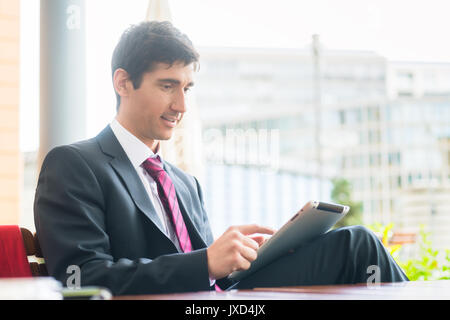 Jeune homme portant un costume d'affaires lors de l'utilisation d'un tablet PC au cours de b Banque D'Images