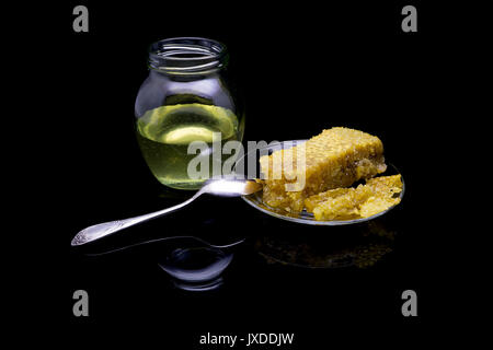 Avec du miel d'abeilles sur une plaque de verre isolé sur un fond noir Banque D'Images