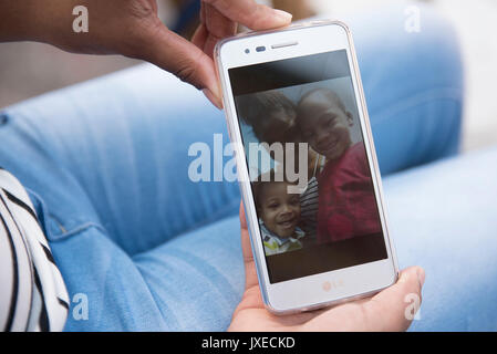 West Palm Beach, Floride, USA. Août 15, 2017. Tranice Smith, 19 ans, est titulaire d'une photo sur son téléphone de elle et ses deux garçons, Terlle, 1, à gauche, et l'Velmando Jr., 2, à Riviera Beach, en Floride, le mardi 15 août 2017. Le vendredi, le père des garçons, Velmando Williams, piégé les deux garçons et leur un mois soeur dans un appartement Riviera Beach et définir l'accueil sur le feu. Credit : Andres Leiva/Le Palm Beach Post/ZUMA/Alamy Fil Live News Banque D'Images