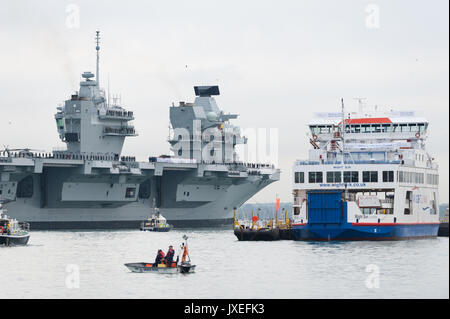 Comme le HMS Queen Elizabeth arrive into​ Le port de Portsmouth, Hampshire, en Angleterre, il passe par un Wightlink Ferry. Banque D'Images