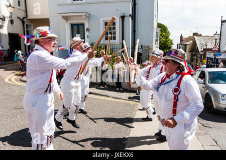 Anglais traditionnel Morris men de Hartley Morris Dancers à l'extérieur de la ville à la rue la semaine annuelle de Broadstairs Folk. La danse de deux lignes portant un pantalon blanc et tee-shirts avec des chapeaux de paille, holding de poteaux. Banque D'Images