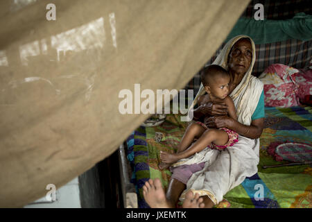 Bogra, Bangladesh. Août 16, 2017. Vieille Femme avec son enfant de subvention s'abritent d'inondation dans la zone Kajla à Bogra. La souffrance des peuples continue comme beaucoup d'entre eux ont quitté leurs foyers avec leur bétail, chèvres, poules et autres animaux de compagnie et ont trouvé refuge dans des zones sûres et bon nombre de ces personnes n'ont pas encore été en mesure de retourner à mesure que l'eau n'a pas entièrement disparu de leurs foyers. Incidents liés aux crues dans Dinajpur, Gaibandha Lalmonirhat et augmenter le nombre de morts à 30 dans les trois derniers jours à travers le pays. Credit : K M Asad/ZUMA/Alamy Fil Live News Banque D'Images