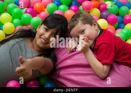 Happy brothers jette sur le gros tas de petites boules multicolores. Banque D'Images