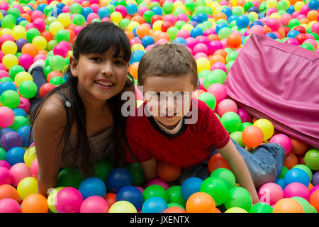 Happy brothers jette sur le gros tas de petites boules multicolores. Banque D'Images