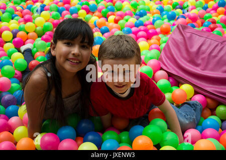 Happy brothers jette sur le gros tas de petites boules multicolores. Banque D'Images