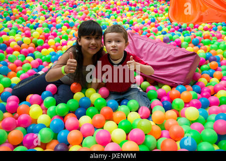 Happy brothers jette sur le gros tas de petites boules multicolores. Banque D'Images