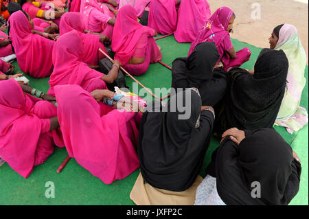 L'Uttar Pradesh, Inde Banda de basse caste et casteless les femmes à s'organiser en mouvement Femmes Gulabi gang de femmes chef Sampat Pal Devi et de lutte avec des tiges de bambou pour l'égalité de droit et de lutte contre la police ou les hommes, les femmes en rose de Gulabi gang et les femmes musulmanes voilées noir Banque D'Images