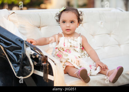 Baby Girl wearing a robe assis sur un chariot à cheval Banque D'Images