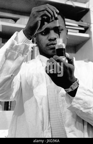 Ernest UN Bates, d'étudiants Noirs américains, Portrait, debout, jusqu'à l'estomac, de face, ca 22 ans, Bates est l'ajout de gouttes de liquide d'un récipient dans un laboratoire, 1958. Banque D'Images