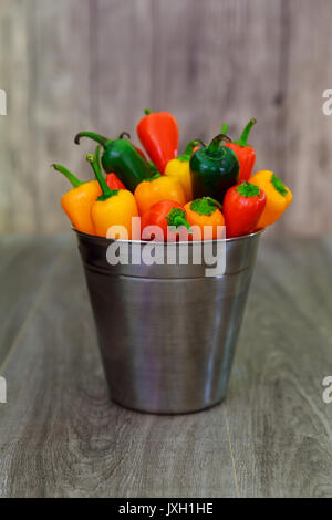 Mini poivrons colorés vue ci-dessus dans un panier sur un fond de bois Banque D'Images