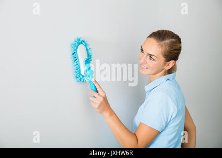 Young Smiling Woman Cleaning mur à l'aide à la maison de la brosse Banque D'Images