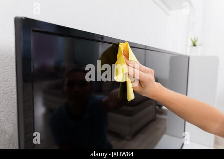 Portrait de femme à l'aide de chiffon pour nettoyer la maison à la télévision Banque D'Images