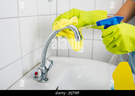 Close-up of Woman main dans le bassin de nettoyage Gants robinet avec salle de bains à l'Éponge Banque D'Images