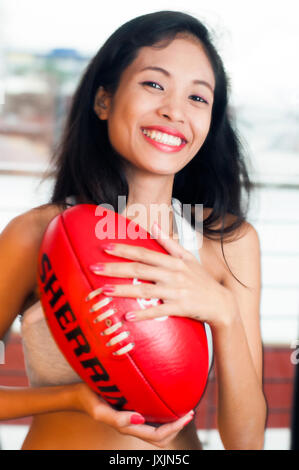 Young Asian woman holding Australian rules football AFL Banque D'Images