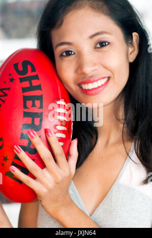 Young Asian woman holding Australian rules football AFL Banque D'Images